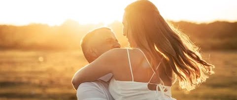 Casal abraçado, cabelo ao vento, contraluz dourado.