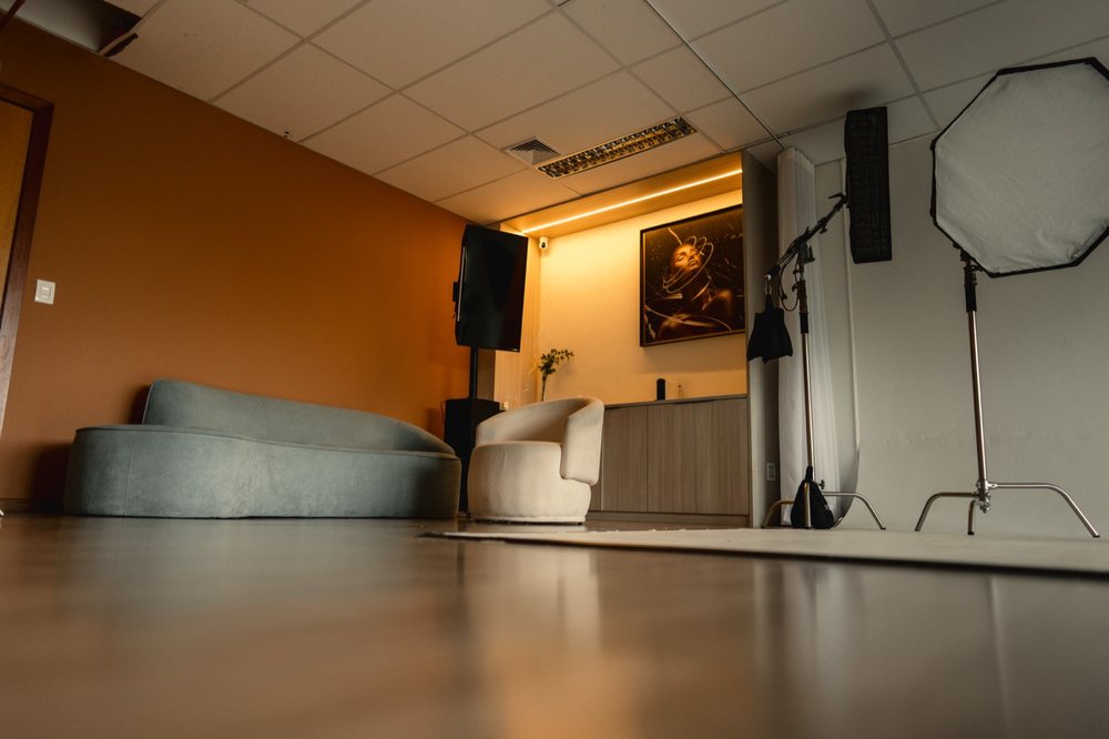 Lounge do Estúdio 403, com sofá e parede em tom terracota.