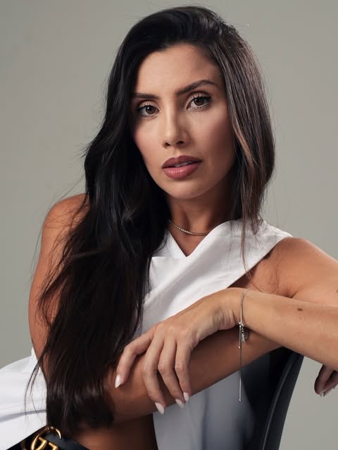 Retrato de mulher sentada, fundo neutro, luz suave.